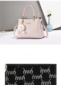 Detail of pink faux leather handbag with monogram pattern and white plush keychain