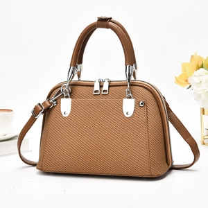 Détail du sac cabas marron à texture tressée avec anses en cuir et finitions argentées