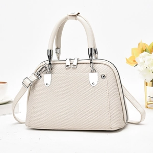 Gros plan du sac à main crème pour femme avec texture tissée et détails en métal argenté