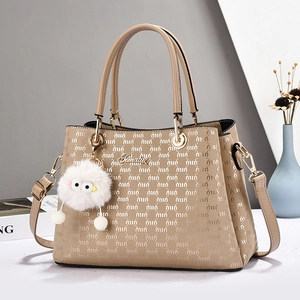 Chic beige crossbody bag with quilted monogram texture and plush charm in home setting