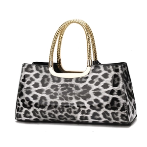 Detailed view of the leopard print handbag featuring high-gloss texture and gold metal handle