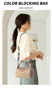 Macro view of high-capacity beige leather pillow bag with knotted handle and wide strap