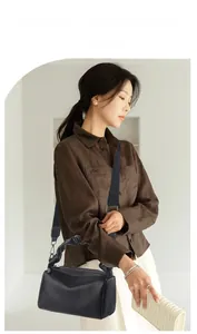Detail view of black lychee leather crossbody bag with pleated handle on female model