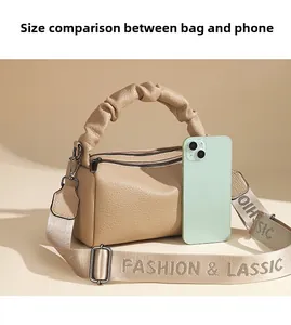 Size comparison of light brown pebbled leather satchel with a smartphone and strap