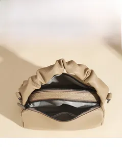 Detailed view of spacious dual-zipper compartments with herringbone lining in beige handbag