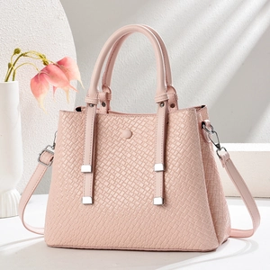 Detail of light pink woven texture crossbody bag with circular handle and thin shoulder strap