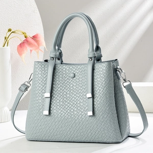 Detail of light blue-grey handbag with woven texture and silver hardware in minimalist setup