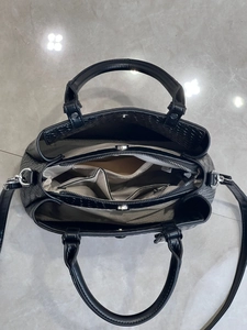 Top view detail of the black handbag's three-compartment interior and silver hardware