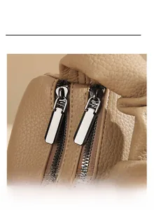 Close-up of smooth dual metal zippers and premium beige leather texture on the bag