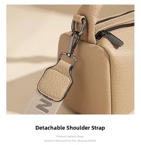 Detail of detachable woven shoulder strap with metallic hook and pebbled leather bag