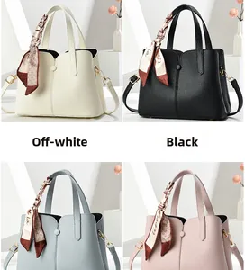 Detail of solid color pebble leather handbags featuring decorative scarves and gold hardware