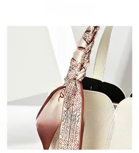 Detail of white lychee leather bag featuring scalloped edge and silk scarf handle wrap