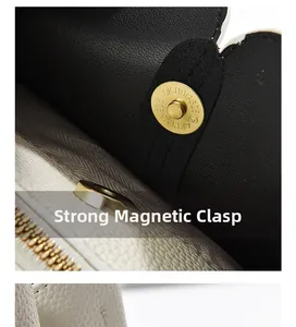 Detail view of gold magnetic snap closure on off-white pebbled leather handbag