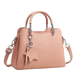 Pink lychee grain leather tote bag with shoulder strap and star pendant on white background