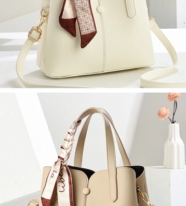 Macro detail of beige pebble leather handbag with gold hardware and decorative silk scarf