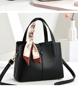 Detail of black lychee grain leather handbag featuring a decorative printed silk scarf handle