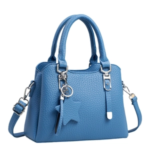 Sac à main bleu en cuir grainé avec pendentif étoile et bandoulière sur fond blanc