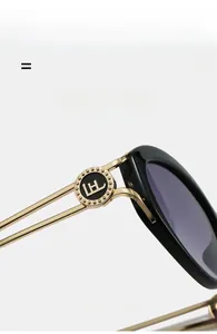 Detail of gold metal hollow temples and logo hinge on black cat-eye sunglasses