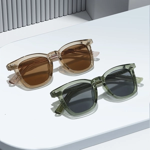 Modische quadratische Sonnenbrille mit transparentem Rahmen und Metallnieten auf weißem Sockel