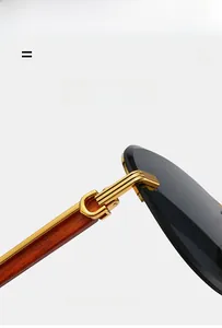 Close-up of golden C-shape metal hinge on wood grain temple of rimless sunglasses