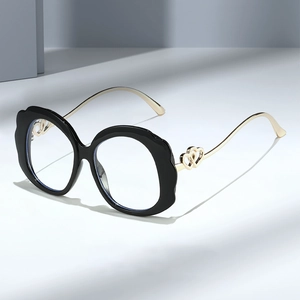 Chic black wavy frame glasses with golden hollow heart metal temples on grey surface