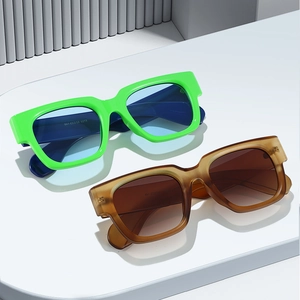 Fashionable square thick frame sunglasses in green and amber on a geometric display