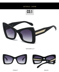 Detail view of large black frame sunglasses with golden woven texture on the temples