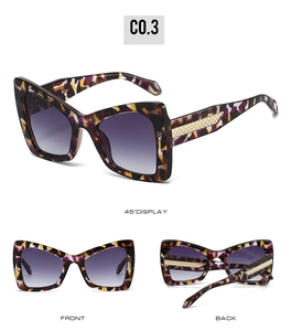 Detail view of cat eye sunglasses with purple tortoiseshell frames and golden woven metal