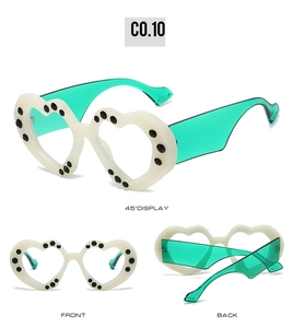 Three angles of white heart-shaped party sunglasses with black dots and green lenses