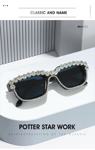 Close-up of rectangular black sunglasses with luxury crystal rhinestones on white platform