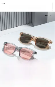 Detail of square sunglasses with tea and gray transparent frames on a minimal white step