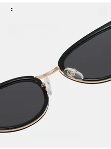Detailed macro view of black sunglasses featuring a golden metal bridge and soft silicone nose pads