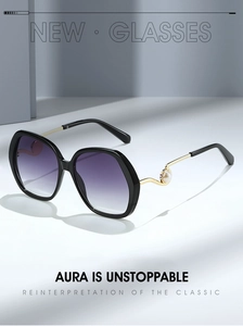Detail of oversized sunglasses featuring wavy gold metal temples with pearl accents