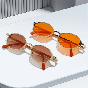 Retro small oval metal sunglasses with orange and amber lenses on a white display stand