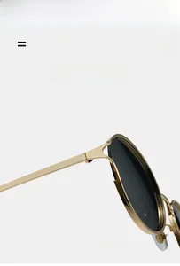 Detail view of lightweight flexible gold frame sunglasses with dark grey lenses