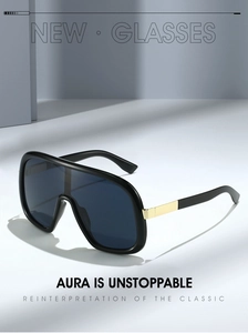 Detail view of black oversized shield sunglasses with gold metal accents on the temple