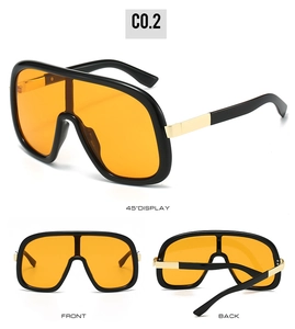 Detail of oversized visor sunglasses with orange lenses and gold metal hinges