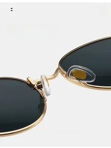 Détail du pont en métal doré et des plaquettes en silicone sur lunettes de soleil rondes