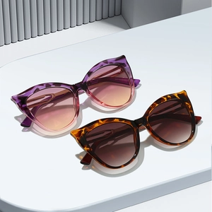 Lunettes de soleil œil-de-chat avec montures violettes et écaille sur socle blanc
