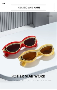 Detail of trendy oval sunglasses with red and yellow frames and gold metal trim