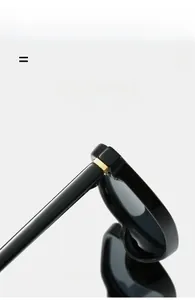 Detail of black small frame sunglasses featuring a golden square hinge accent and sleek temple
