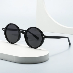 Lunettes de soleil ovales noires rétro avec détails argentés sur présentoir moderne