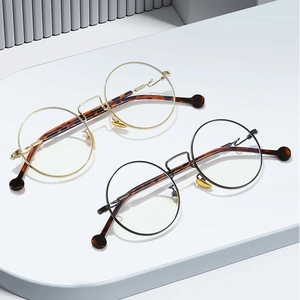 Minimalist round metal frame glasses with wavy temples and tortoiseshell tips in gold and black