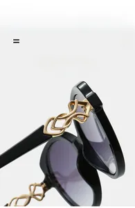 Detail shot of sunglasses with golden metal woven hinges and sleek black wide frames