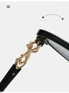 Detail of premium gold metal hinges with intricate cutout design on black sunglasses