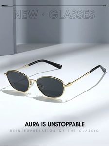 Detail of vintage cat-eye sunglasses with gold metal frames and dark lenses on a grey surface