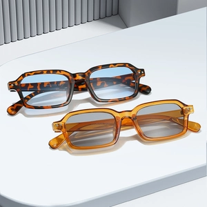 Fashionable rectangle frame sunglasses with metal rivet details on a white display stand