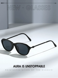 Detail of sleek black cat-eye sunglasses with oval metal hinge accents on slim temples