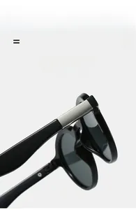 Close-up of black sunglasses featuring a silver brushed metal hinge and elastic frame detail