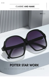 Close-up of oversized black oval sunglasses with purple gradient lenses on a display